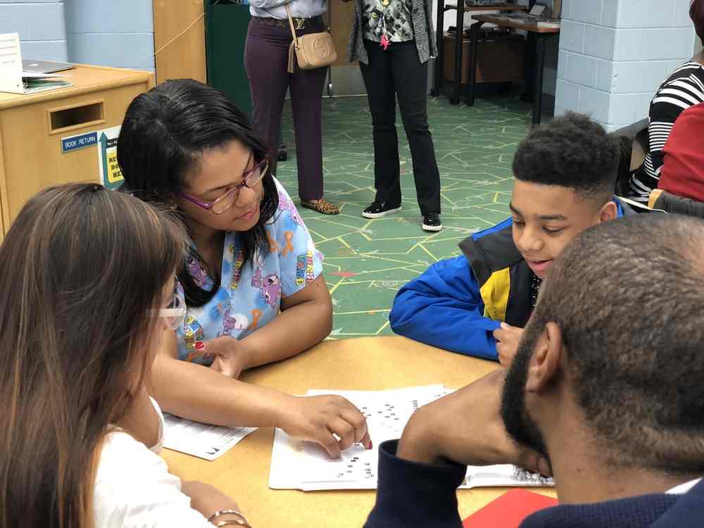 A student sits with four staff members at a table, discussing a report they're all looking at