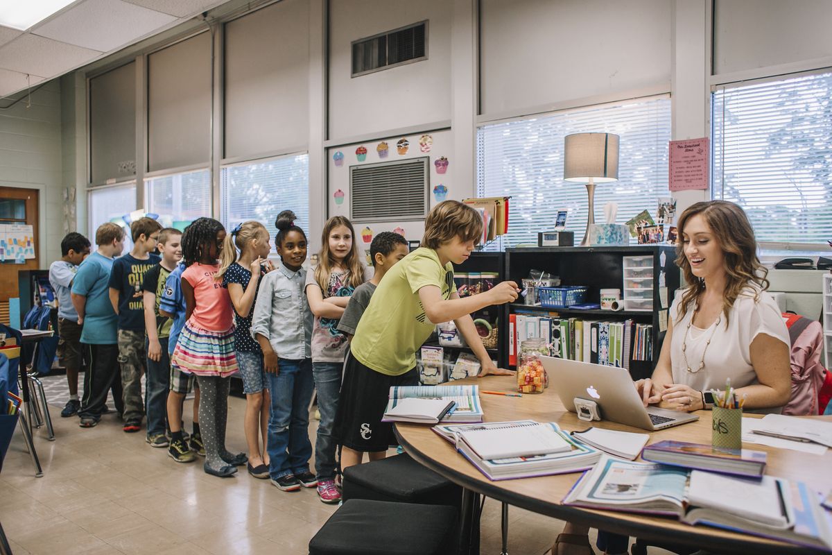 A teacher runs a PBIS Reward store - with students lined up and one student choosing a reward
