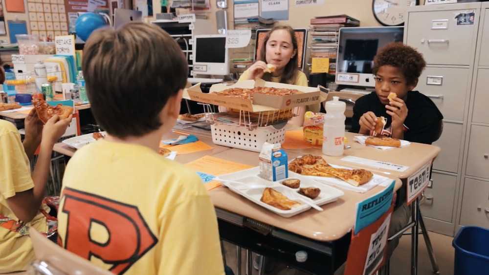 Students enjoying a pizza party at their desks in a classroom