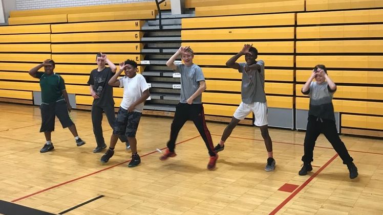 Students in a gymnasium doing a dance from the video game "Fortnite"