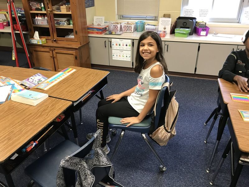 Student sitting at a desk in class smiling